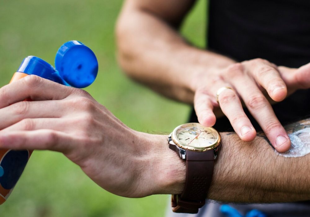 hombre colocando bloqueador solar sobre su brazo